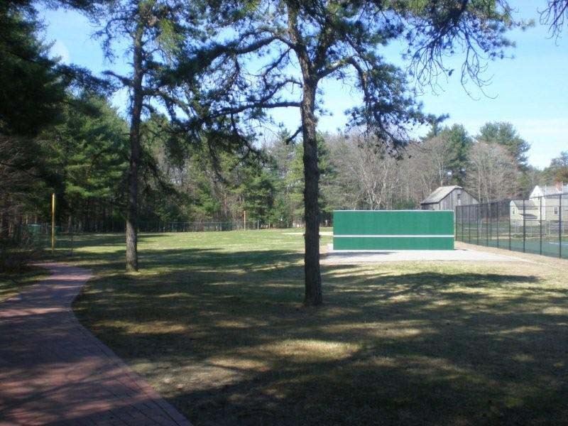 tennis bang board situated between brick pathway and tennis courts 