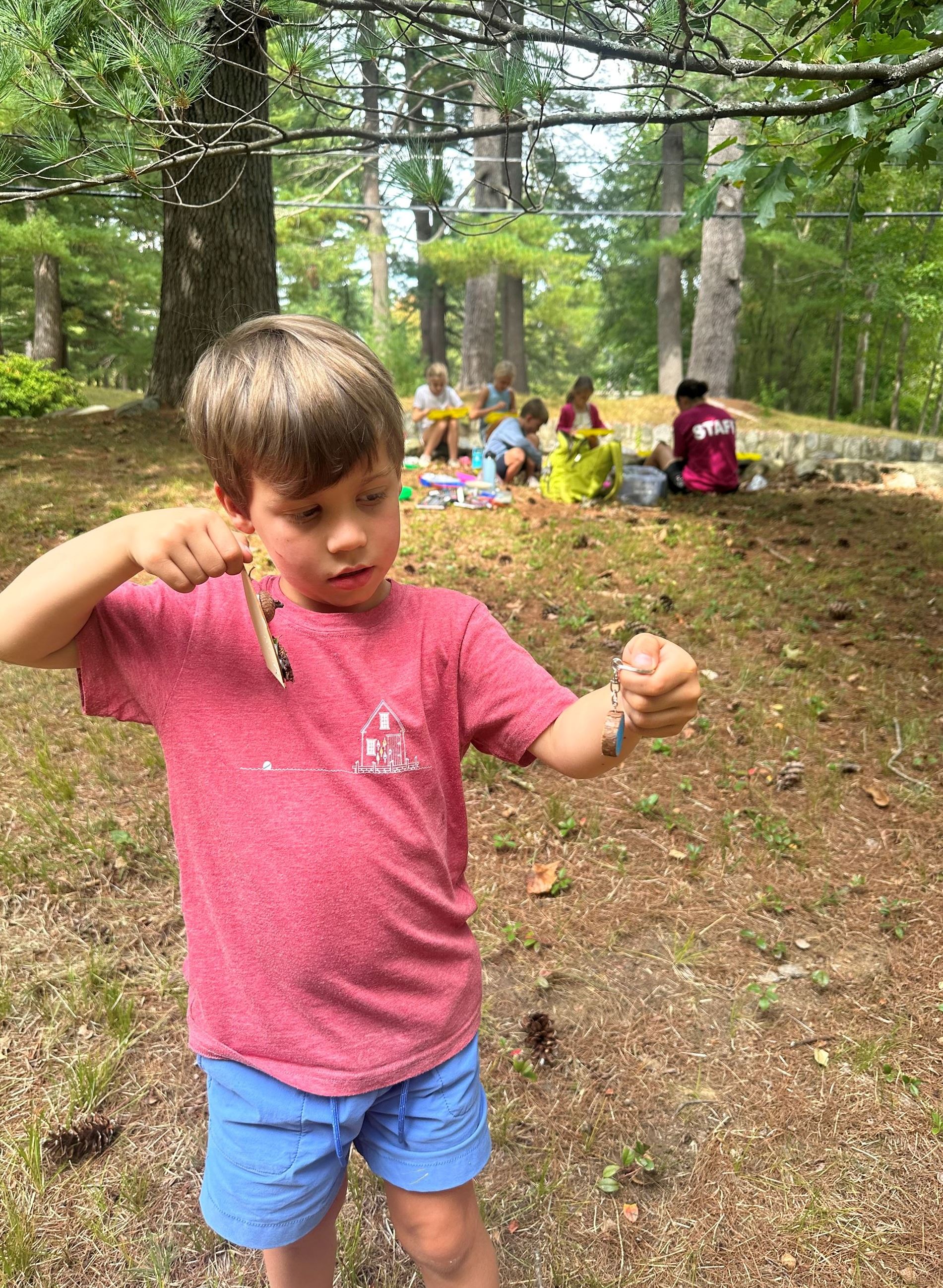 Photo of child while holding his art project in the woods